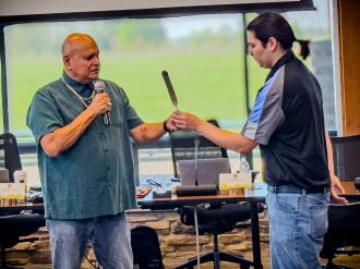 An instructor passes a feather to a student.