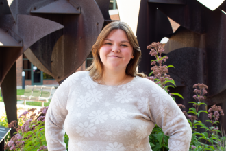 Headshot of Lyndsey Sootsman in a patterned sweater outside of schneider hall