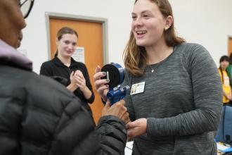 A student holds medical equipment while another looks on.