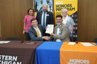 President Kavalhuna and Kellogg Community College's president shake hands at a table.