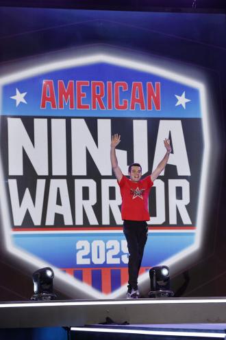 Michael Vasilevich stands in front of a sign that reads "American Ninja Warrior 2025."