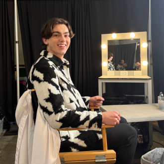 Jack Austin sits in a director's chair next to a vanity mirror.