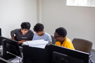 Three high school students sitting at computers. 