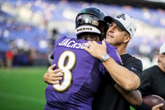 John Harbaugh hugs Baltimore Ravens quarterback Lamar Jackson.