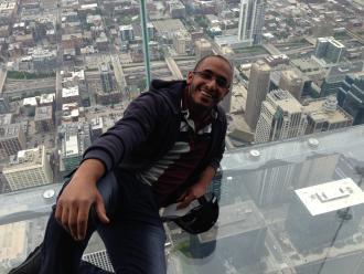ali sitting on the sky-high glass at the Sears Tower 