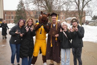 A family poses for a photo outside with Buster Bronco.