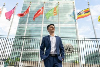 Mehran Najafi stands outside under several international flags.
