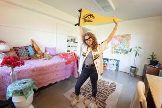 Hope Donovan stands in her room holding a WMU flag.