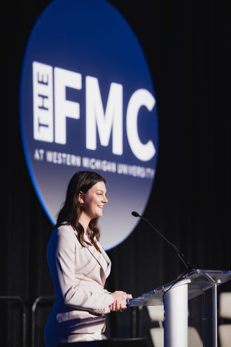 Avery Knoll introduces a speaker at The FMC