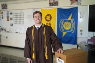 Jordan Rundhaug poses for a photo in his graduation regalia.