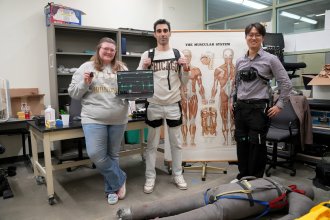 Autumn Hotopp, undergraduate student, and Mostafa Zadeh, doctoral student, showcase the wearable equipment alongside Dr. Sang Kang.