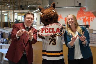 buster bronco holding FCCLA sign with people on sides