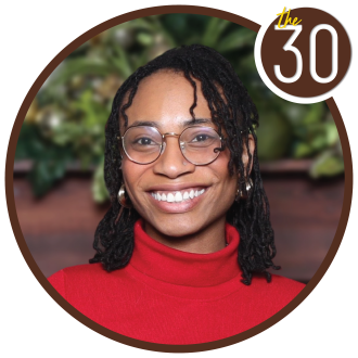 Jana Walker, B.B.A.’22, M.S.A.’23 in front of trees in a red sweater