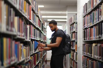 Student standing in the stacks at Waldo Library looking at a map.
