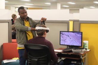 Magi assists a student with his VR headset. 