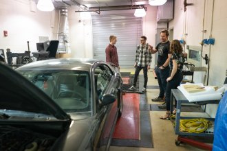 Students standing around a vehicle. 