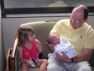Children and their grandpa sitting on chair.