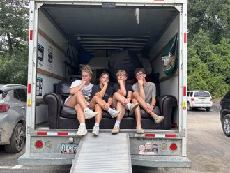 Group of students sitting in U-Haul truck.