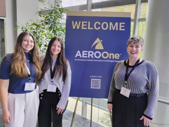 Two students and a faculty member at a conference fair.