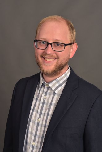 Professional individual smiling slightly, wearing business attire