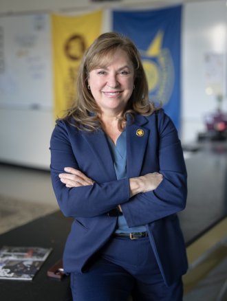 A portrait o f Dr. Ashlyn Kuersten in front of flags representing WMU and Michigan State Police.