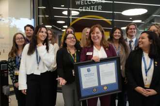 Dr. Ashlyn Kuersten is surrounded by students after receiving an award certificate.
