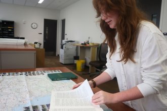 Intern Halle Martin looking at Leopold Janaushcek's research journal and a map.
