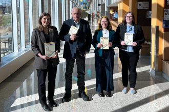 Faculty and students hold copies of their new book in Sangren Hall on Western Michigan University's main campus.