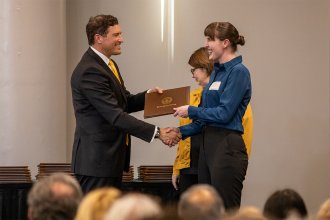 President Russ Kavalhuna gives student Erica MacQueen an award for being the Presidential Scholar in biological sciences.