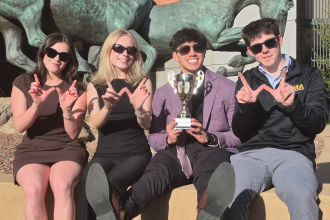 Sales students wearing sunglasses and holding the Desert Cup after their win.