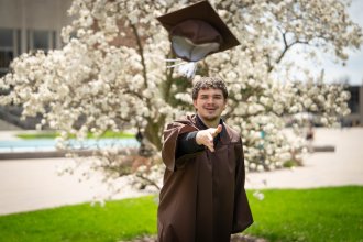 Aidan Ralko tosses his graduation cap into the air.