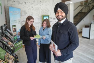 Arshpreet Singh stands with coworkers inside the Discover Kalamazoo office.