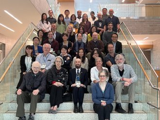 A group of Asian studies scholars sits on the stairs at WMU after an academic conference.