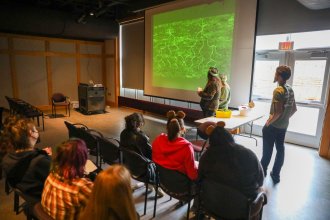 A student presents in front of a classroom.