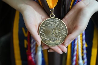 Hands hold a Medallion Scholar medal.