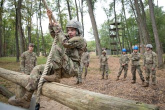 Molly Cochran swings over an obstacle at Fort Custer during military training.