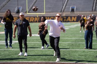 A student throws a football on the field.