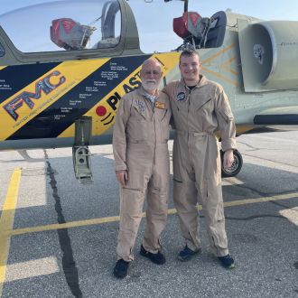 Student and person standing in front of fighter jet.