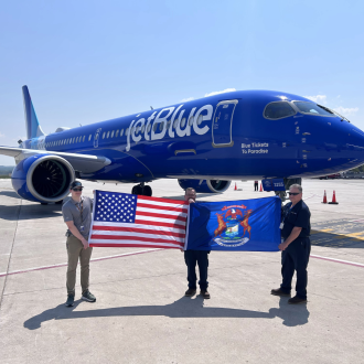 Students holding flag in front of plane.