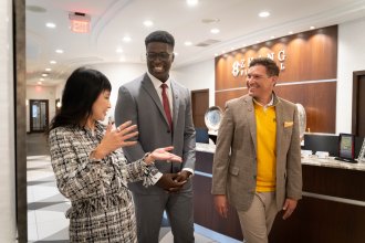 Lynn Chen-Zhang, Mo Tall and President Russ Kavalhuna walk through the hall at Zhang Financial.
