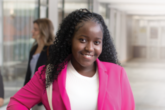 Hosanna Ndikumana standing in the hallway in a pink blazer.