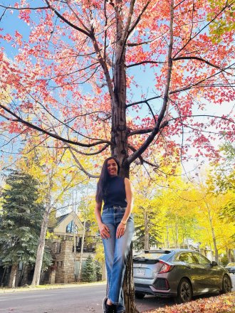 An international student poses in a fall landscape.