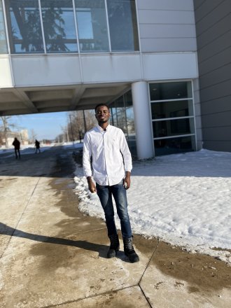 An international student poses on campus during winter. Snow is on the ground.
