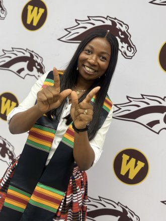An international student poses on campus during graduation time.