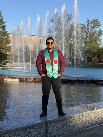 An international student poses wearing the flag of his country during graduation season.