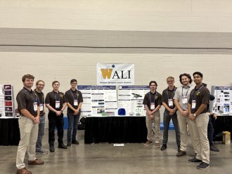 An international student posing with classmates at an engineering event.