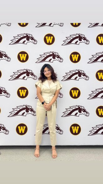 An international student posing on campus during graduation season.