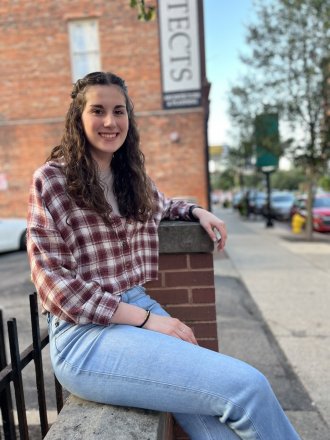BSW student, Hailee Hamilton sitting outdoors in front of a brick building.