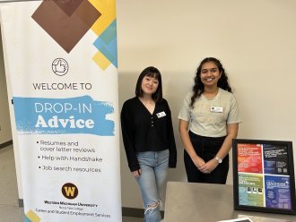 An international student and her friend pose next to a career services sign.