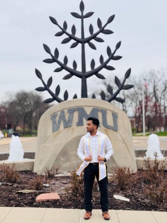 An international student poses on campus during graduation season.